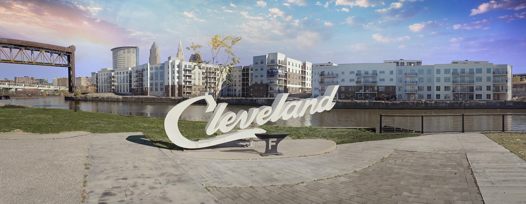 a sign in front of water and a city skyline behind it